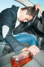 Young driver with bottle in hand sleeps in the car.